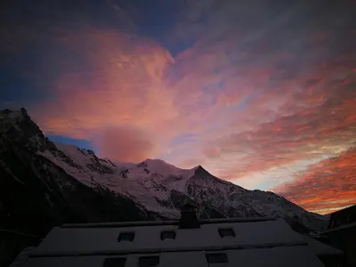 a sunset over a snowy mountain with a building at Le Gypaète in Chamonix-Mont-Blanc