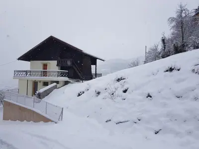 a house on a snow covered hill with a building at Chalet avec terrasse et vue sur le Mt-Blanc in Sallanches
