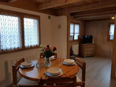 a dining room with a wooden table with flowers on it at Chalet avec terrasse et vue sur le Mt-Blanc in Sallanches