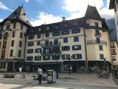 a large white building with a pointed roof at Appartement cosy au centre de Chamonix avec parking - FR-1-507-42 in Chamonix-Mont-Blanc