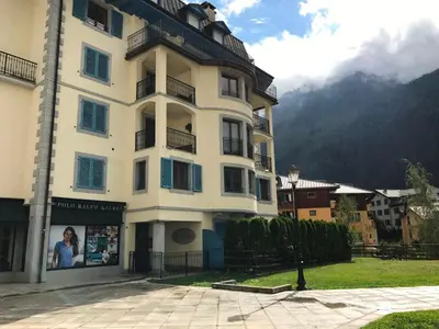 a large white building in front of a mountain at Appartement cosy au centre de Chamonix avec parking - FR-1-507-42 in Chamonix-Mont-Blanc