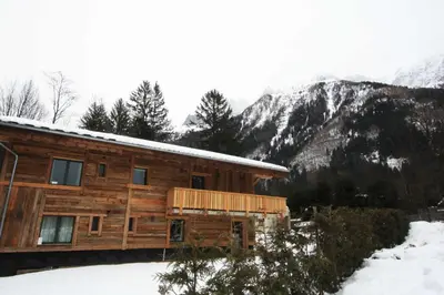 a log cabin in the snow with mountains in the background at Chalet des Amis appt 1 - Chamonix All Year in Chamonix-Mont-Blanc