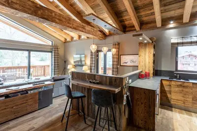 a kitchen with wooden ceilings and a bar with stools at Chalet des Amis appt 2 - Chamonix All Year in Chamonix-Mont-Blanc