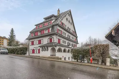 a large white building with red windows on a street at Appartement Odyssée - Welkeys in Megève