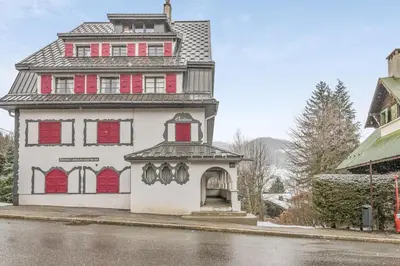 a large white house with red windows on a street at Appartement Odyssée - Welkeys in Megève
