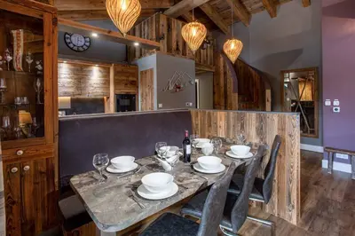 a wooden table with plates and wine glasses on it at Chalet des Amis- Chamonix All Year in Chamonix-Mont-Blanc