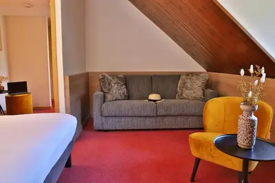 a room with a bed and a couch and a table at SOWELL HOTELS Mont Blanc et SPA in Saint-Gervais-les-Bains