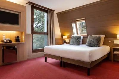a bedroom with a bed and a tv and windows at SOWELL HOTELS Mont Blanc et SPA in Saint-Gervais-les-Bains