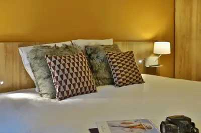 a bed with two pillows and a book on it at SOWELL HOTELS Mont Blanc et SPA in Saint-Gervais-les-Bains