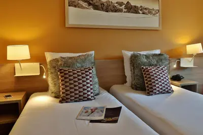 a hotel room with two beds with pillows and a book at SOWELL HOTELS Mont Blanc et SPA in Saint-Gervais-les-Bains