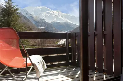 a chair on a balcony with a view of a mountain at SOWELL HOTELS Mont Blanc et SPA in Saint-Gervais-les-Bains