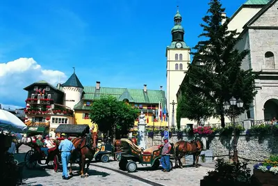 a horse drawn carriage in front of a building with a clock tower at Les Clochettes in Megève
