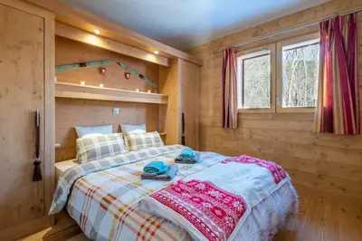 a bedroom with a bed in a wooden cabin at IRIS A3 Chalet Delys in Les Houches