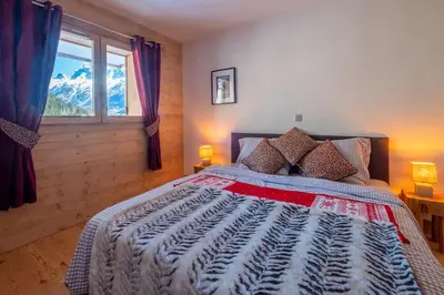 a bedroom with a large bed and a window at IRIS A3 Chalet Delys in Les Houches