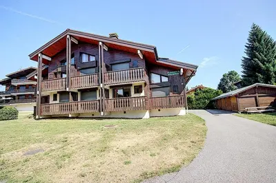 a large wooden house with a large deck on a yard at Le chalet des neiges 2 est au calme situé à 5 mn à pied du centre il est composé d'1 chambre avec lit double plus canapé convertible parking privé sur place et arrêt navette gratuite à 30 m in Les Carroz d'Araches