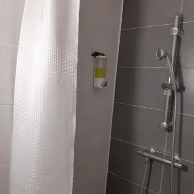 a shower with a white shower curtain in a bathroom at Le chalet des neiges 2 est au calme situé à 5 mn à pied du centre il est composé d'1 chambre avec lit double plus canapé convertible parking privé sur place et arrêt navette gratuite à 30 m in Les Carroz d'Araches