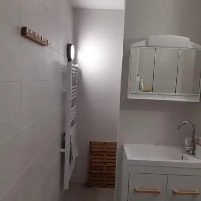 a small white kitchen with a sink and a mirror at Le chalet des neiges 2 est au calme situé à 5 mn à pied du centre il est composé d'1 chambre avec lit double plus canapé convertible parking privé sur place et arrêt navette gratuite à 30 m in Les Carroz d'Araches