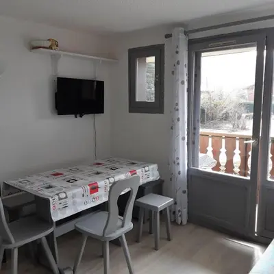 a room with a table and chairs and a window at Le chalet des neiges 2 est au calme situé à 5 mn à pied du centre il est composé d'1 chambre avec lit double plus canapé convertible parking privé sur place et arrêt navette gratuite à 30 m in Les Carroz d'Araches