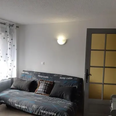a black leather couch in a living room at Le chalet des neiges 2 est au calme situé à 5 mn à pied du centre il est composé d'1 chambre avec lit double plus canapé convertible parking privé sur place et arrêt navette gratuite à 30 m in Les Carroz d'Araches