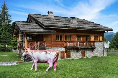 a cow standing in front of a log house at Beautiful Nirvana in Megève