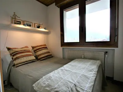 a bedroom with a bed with two pillows and two windows at Charmant T2 Chamonix avec balcon, accepte animaux - FR-1-507-45 in Chamonix-Mont-Blanc