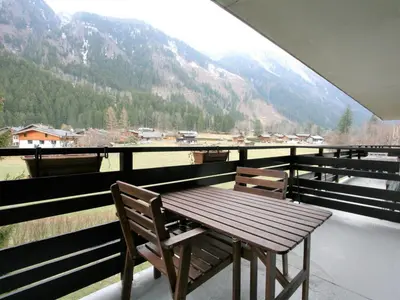 a wooden table and chairs on a balcony with a view at Charmant T2 Chamonix avec balcon, accepte animaux - FR-1-507-45 in Chamonix-Mont-Blanc