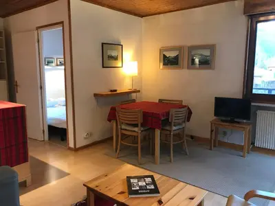 a living room with a table and a television at Charmant T2 Chamonix avec balcon, accepte animaux - FR-1-507-45 in Chamonix-Mont-Blanc