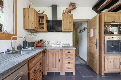 a kitchen with wooden cabinets and a stainless steel refrigerator at Chalet Taconnaz - Warm & Cosy 3BR Chalet with Fireplace in Nature - By Cozee Rentals in Les Houches