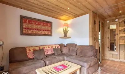 a living room with a brown couch and a table at Appartement confortable à Megève | 46m² | Vue sur montagne in Megève