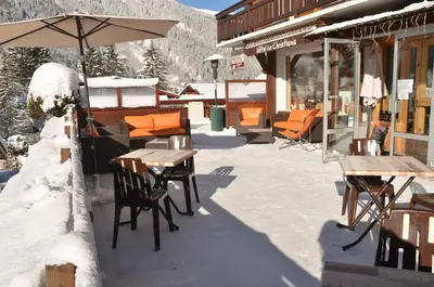a patio with tables and chairs and an umbrella at Hotel Le Christiania in Les Contamines-Montjoie