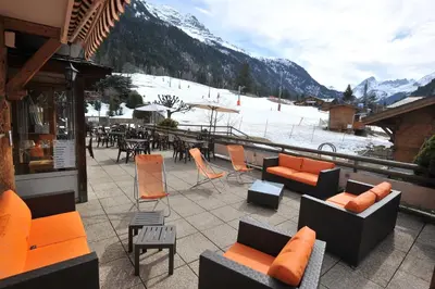 a balcony with couches and chairs and a ski slope at Hotel Le Christiania in Les Contamines-Montjoie