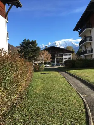a path in front of a building with mountains in the background at MONT BLANC HOLIDAYS dans résidence avec Gardien in Sallanches