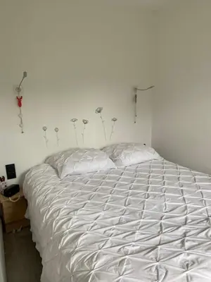 a white bed in a bedroom with flowers on the wall at MONT BLANC HOLIDAYS dans résidence avec Gardien in Sallanches