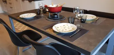 a table with plates and wine glasses on it at Elégant et moderne, au pied du Mont-Blanc in Saint-Gervais-les-Bains