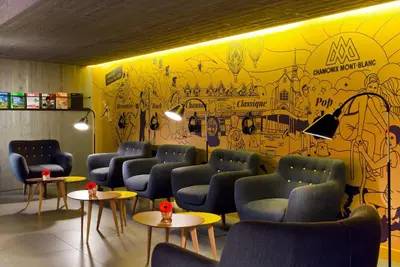 a waiting room with blue chairs and a yellow wall at Heliopic Hotel & Spa in Chamonix-Mont-Blanc