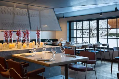 a restaurant with tables and chairs and large windows at Heliopic Hotel & Spa in Chamonix-Mont-Blanc