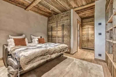 a bedroom with a bed and a wooden wall at Le Hameau du Renard Blanc in Saint-Gervais-les-Bains