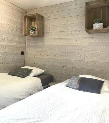 two beds in a room with white walls at Chalet le petit Nicolas, jacuzzi, vue Mont Blanc in Chamonix-Mont-Blanc