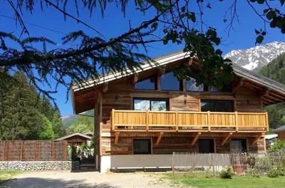 a log cabin with a deck and mountains in the background at Chalet le petit Nicolas, jacuzzi, vue Mont Blanc in Chamonix-Mont-Blanc