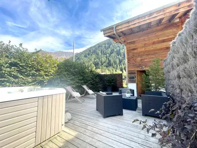 a deck with chairs and a tub on a house at Chalet le petit Nicolas, jacuzzi, vue Mont Blanc in Chamonix-Mont-Blanc