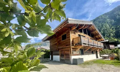 a wooden house with a balcony in the mountains at Chalet le petit Nicolas, jacuzzi, vue Mont Blanc in Chamonix-Mont-Blanc