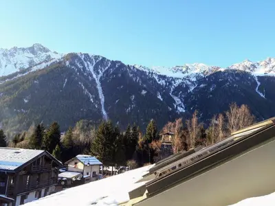 a train station with snowy mountains in the background at Le Chamoniard Volant in Chamonix-Mont-Blanc