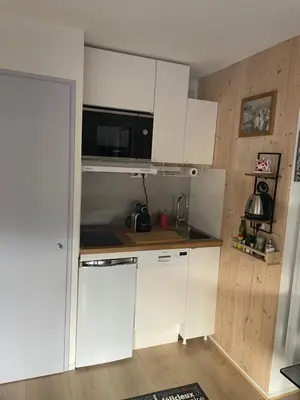 a small kitchen with white cabinets and a microwave at Studio Turquoise quartier Grattague vue MontBlanc in Saint-Gervais-les-Bains