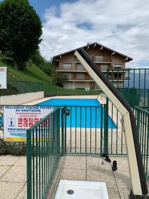 a gate to a swimming pool with a slide at Studio Turquoise quartier Grattague vue MontBlanc in Saint-Gervais-les-Bains