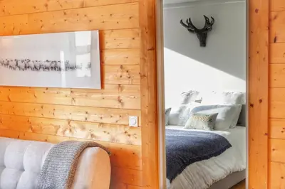 a bedroom with a wooden wall with a mirror at La Ménandière in Megève