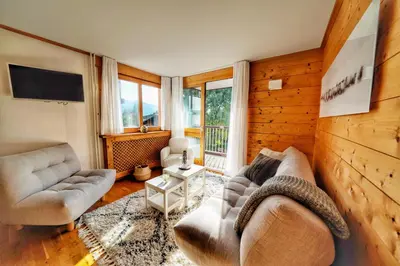 a living room with two couches and a tv at La Ménandière in Megève