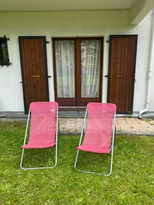 two pink chairs sitting in the grass in front of a house at Appartement style chalet avec grande terrasse et parking prive in Chamonix-Mont-Blanc