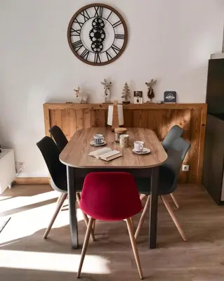 a dining room table with chairs and a clock on the wall at Mont Blanc 43, vue Mont Blanc , balcon, parking in Chamonix-Mont-Blanc
