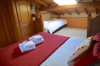 a bedroom with two beds with red sheets and towels at Chalet Roseau in Megève