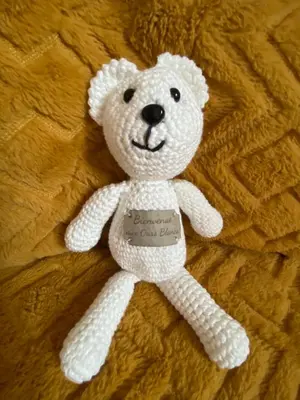 a white stuffed teddy bear laying on a blanket at Les Ours de Combloux in Combloux